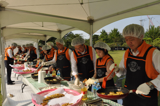 지난 25일 경기 안양 호계동 코스콤 연구센터에서 코스콤 임직원 20여 명이 안양지역 독거노인과 저소득가정에 전달할 전을 부치고 있다. 코스콤 제공